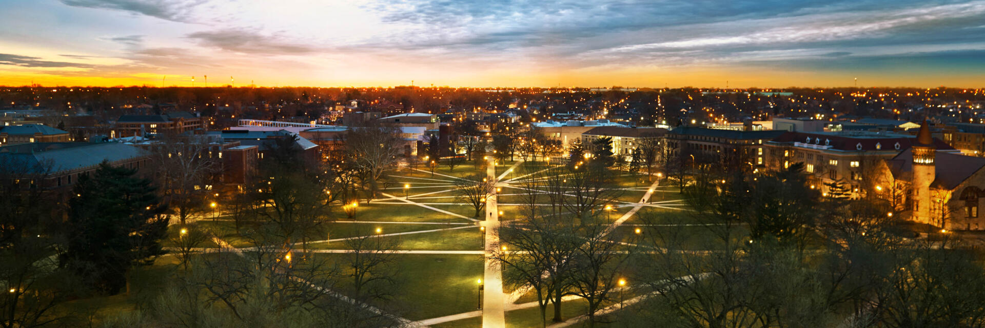 The Ohio State Oval at sunset with campus lights shining bright