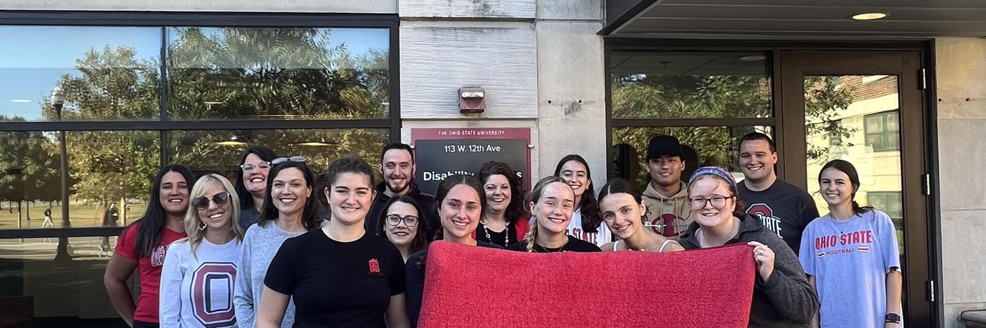 Staff members show off their Buckeye Spirit wearing Scarlet and Gray attire in front of Baker Hall.