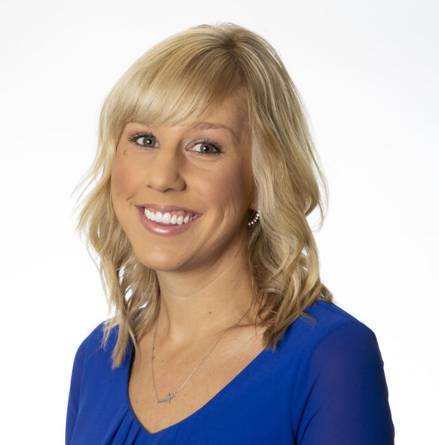 Kelly Bonice - A smiling white woman with shoulder length wavy blonde hair with bangs. She is wearing a blue blouse with a v-neck. She is wearing a silver necklace and earrings.