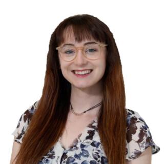 A smiling white woman a white woman with brown hair wearing a floral blouse and light brown glasses.