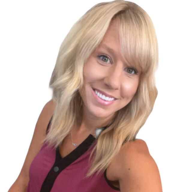 A white woman with wavy blonde hair with bangs wearing a pink blouse with a v-neck.