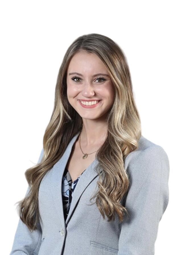 A white woman with light brown hair, wearing a blazer, floral blouse, and necklace.