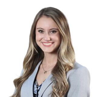 Madalyn Lyons - A white woman with light brown hair, wearing a blazer, floral blouse, and necklace.