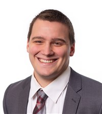 Paul Kraemer, a white male with short brown hair wearing a white shirt, gray suit and plaid tie.