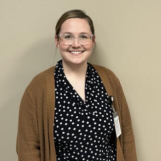 Tiffany Smith, a white woman with brown hair wearing glasses, a nose ring, blouse and a cardigan.