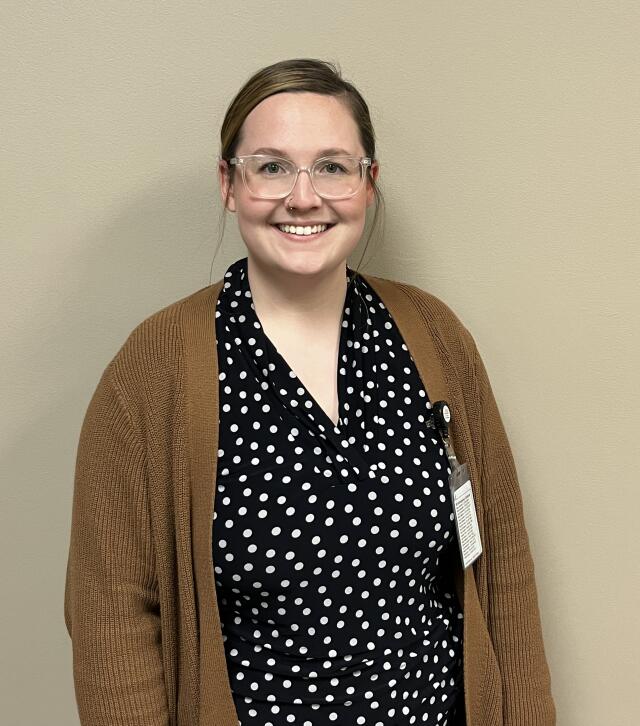 Tiffany Smith, a white woman with brown hair wearing glasses, a nose ring, blouse and a cardigan.